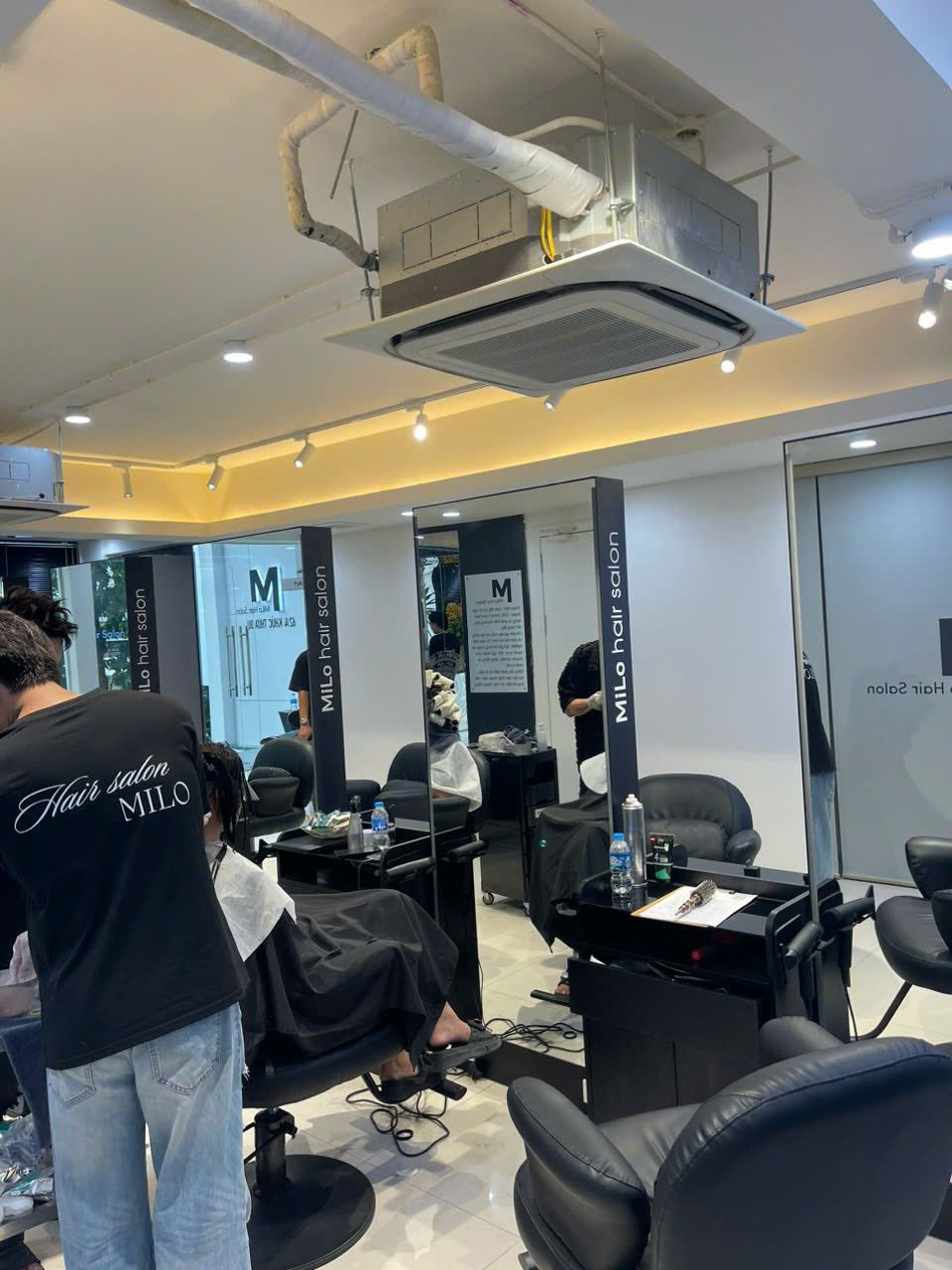 Khu ghế cắt và gương gắn logo MiLo Hair Salon đã hoàn thiện, khách đang sử dụng - Nội Thất Hà Tuấn LX