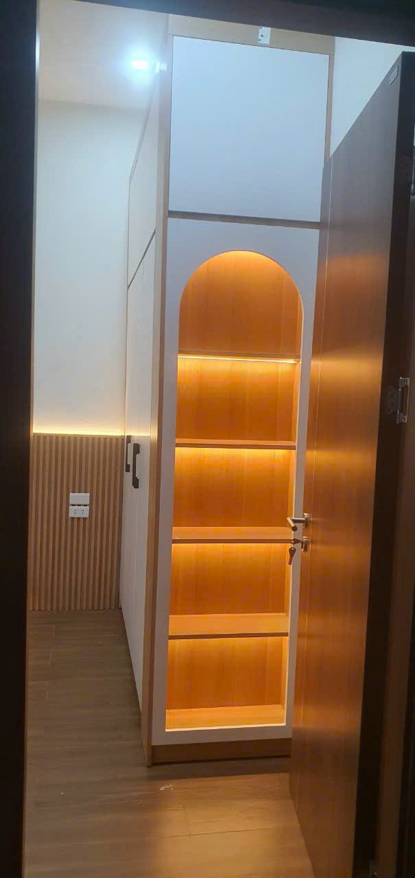 Tủ trang trí cao với hốc vòm đèn LED vàng ấm, cạnh lối cửa - Nội Thất Hà Tuấn LX