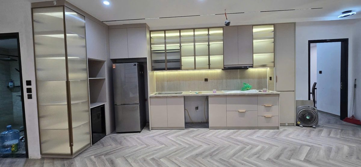 Tủ bếp chữ I dài cánh trắng xám, hệ tủ kính đèn LED sang trọng, tủ lạnh âm - Nội Thất Hà Tuấn LX